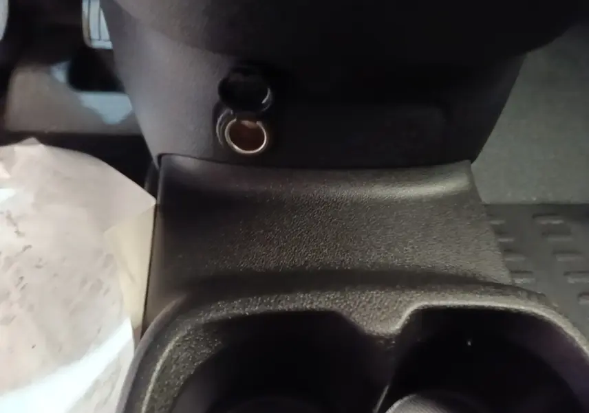 Gros plan sur la prise 12V et porte-gobelets noirs au centre de la console d'un Peugeot Partner blanc 2020.