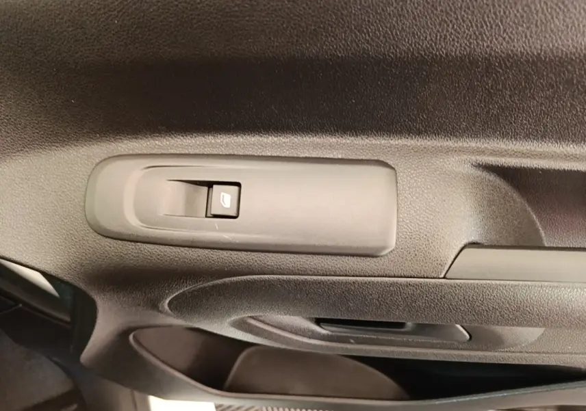 Gros plan sur la commande de lève-vitre côté conducteur dans l'intérieur noir du Peugeot Partner blanc 2020.