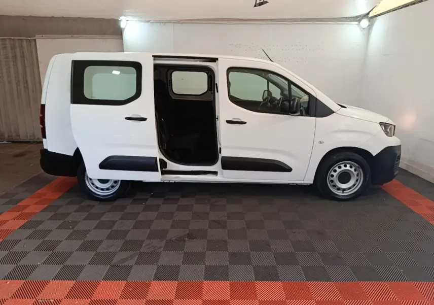 Vue latérale droite d’un Peugeot Partner blanc 2020 avec porte coulissante ouverte en intérieur.