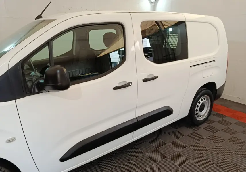 Vue de profil côté gauche du Peugeot Partner blanc avec portes coulissantes et protections latérales noires.