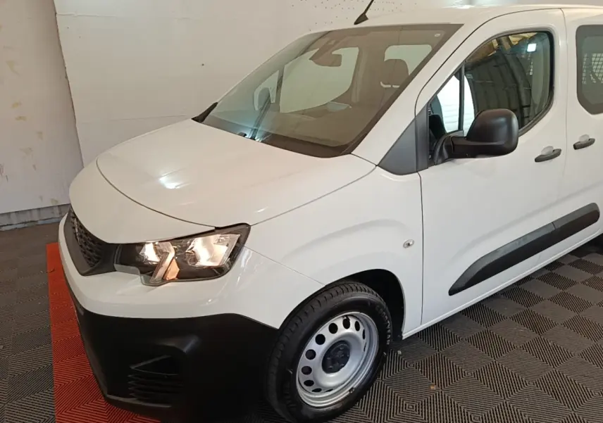 Vue 3/4 avant droit d’un Peugeot Partner blanc avec pare-chocs noirs et jantes acier simples.