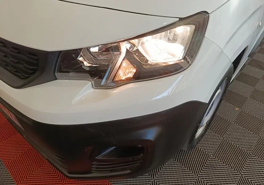 Gros plan sur l'avant droit blanc du Peugeot Partner 2020 avec phare allumé et pare-chocs noir mat.