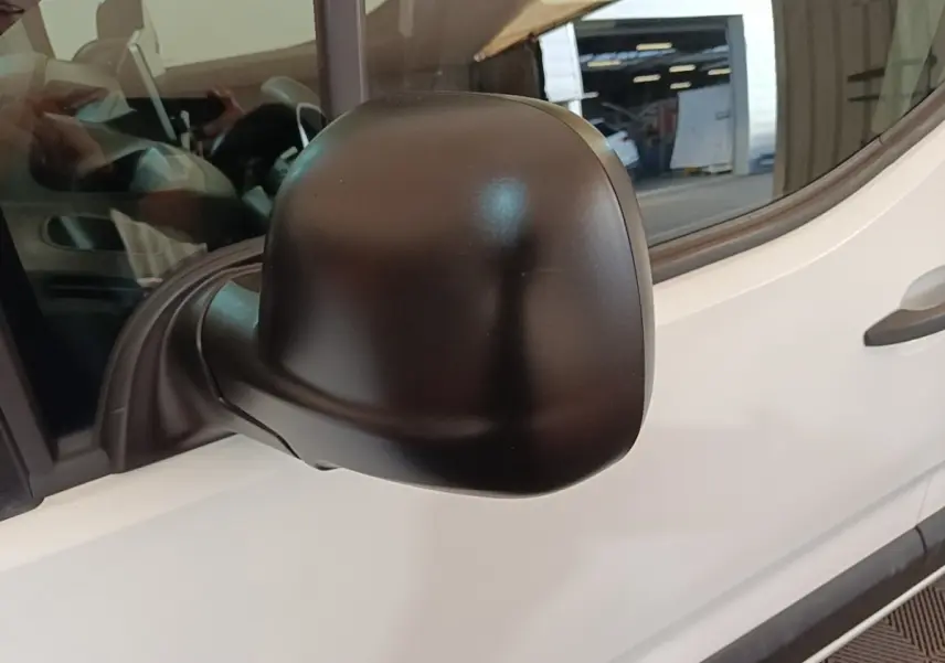 Gros plan sur le rétroviseur noir côté conducteur du Peugeot Partner blanc, vue latérale avant.