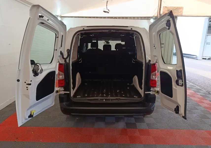 Vue arrière du Peugeot Partner blanc 2020 avec portes battantes ouvertes et cloison grillagée visible dans l’espace de chargement.