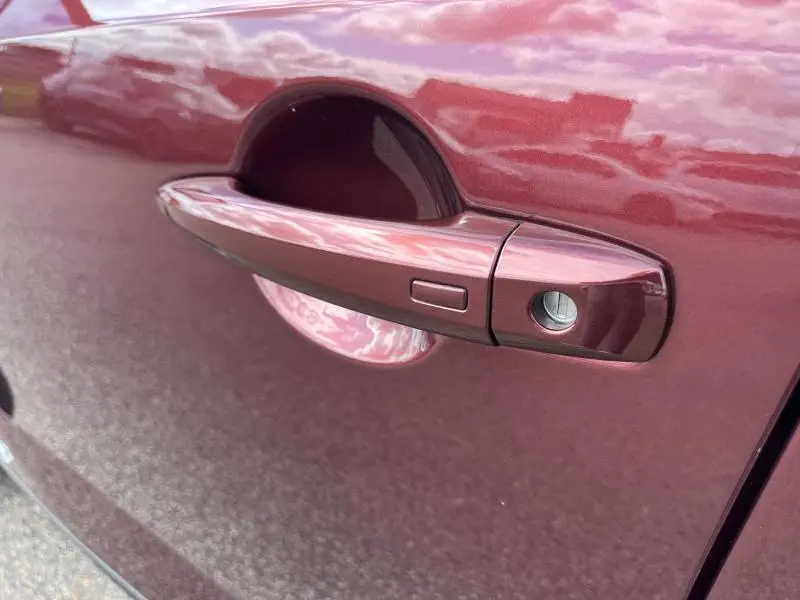 Poignée de porte côté gauche du Nissan Qashqai e-POWER 2023 en Rouge Passion avec bouton d'ouverture sans clé.