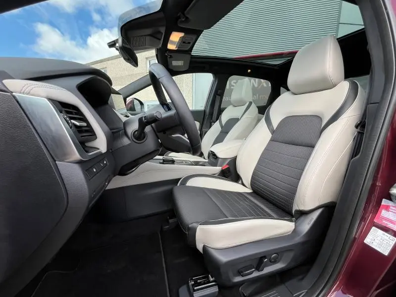 Intérieur avant droit du Nissan Qashqai e-POWER 2023 Rouge Passion avec sièges cuir bicolores et toit panoramique.