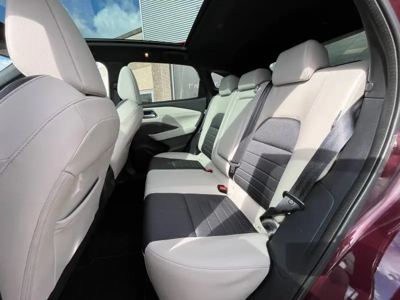 Vue côté gauche de la banquette arrière bicolore cuir clair et noir du Nissan Qashqai e-POWER Rouge Passion avec toit panoramique.