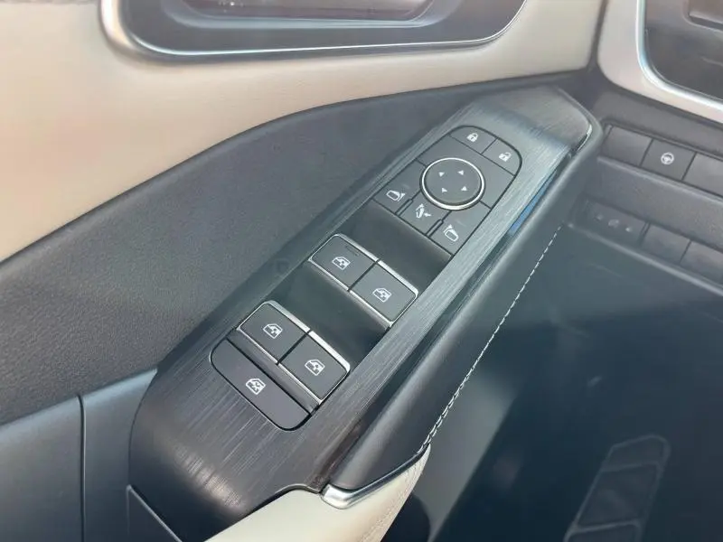 Gros plan sur la commande des vitres et rétroviseurs côté conducteur du Nissan Qashqai e-POWER 2023 avec finition cuir beige et noir.