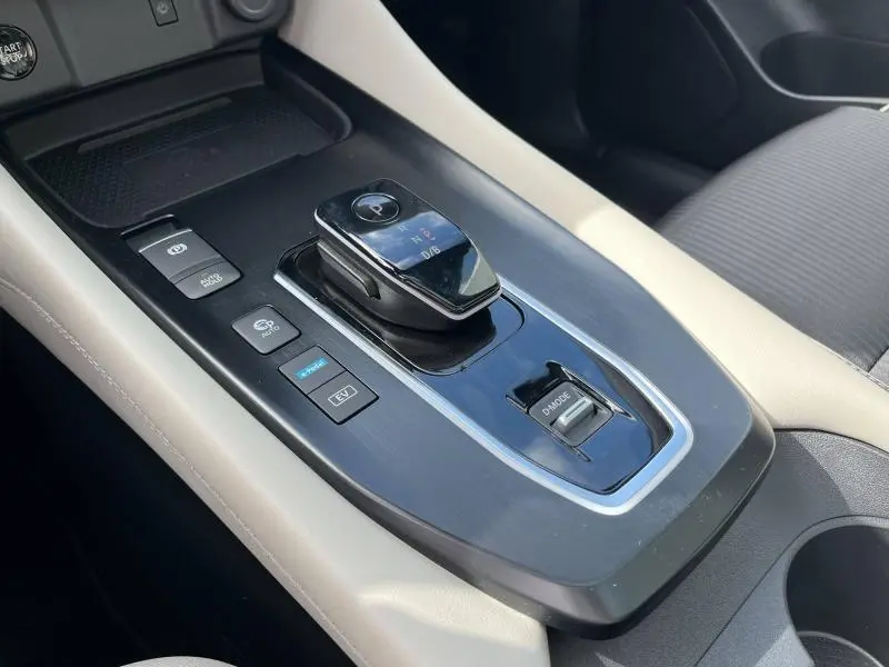 Gros plan sur la console centrale noire et beige du Nissan Qashqai e-POWER 2023, avec levier de vitesses et commandes.