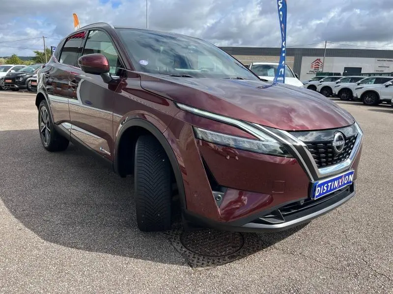 Nissan Qashqai e-POWER 2023 rouge Passion vu en 3/4 avant droit, avec jantes alliage et calandre distinctive.