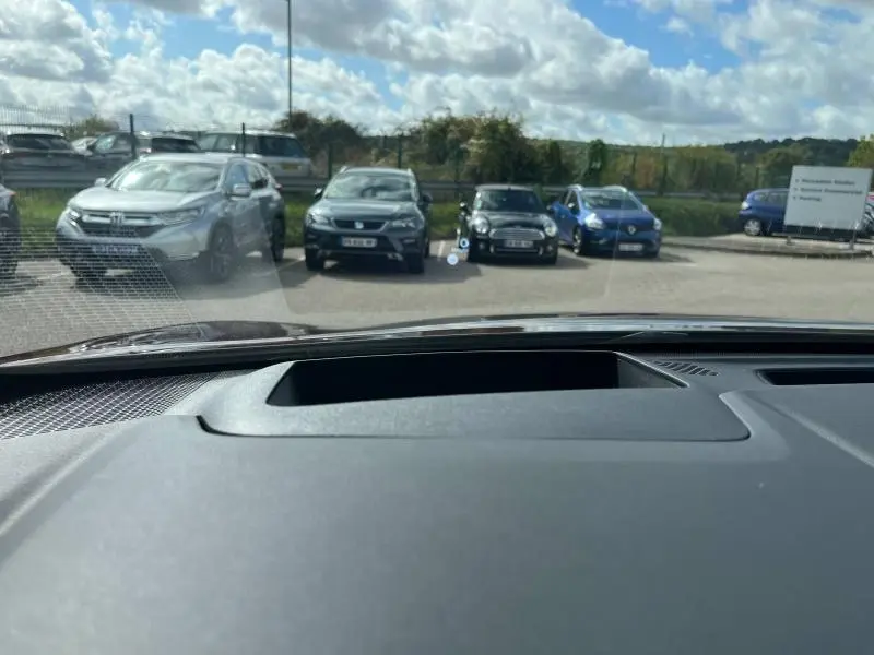 Vue depuis l'habitacle d'un Nissan Qashqai e-POWER rouge Passion, montrant le pare-brise et le tableau de bord noir.