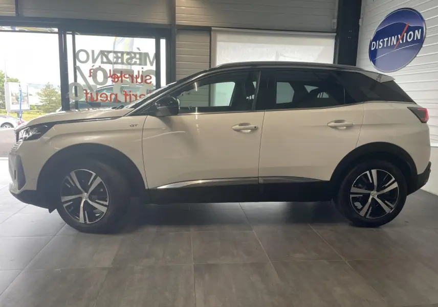 Peugeot 3008 GT blanc nacré vue de profil côté gauche, toit noir et jantes alliage bi-ton visibles en intérieur showroom.