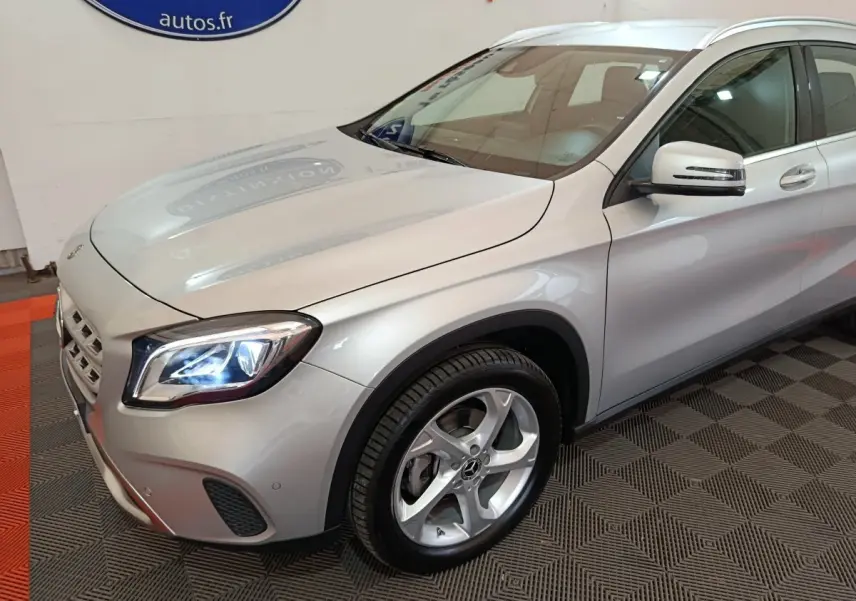Vue 3/4 avant droit d'un Mercedes GLA 200 d gris clair avec phares LED allumés et jantes alliage cinq branches.