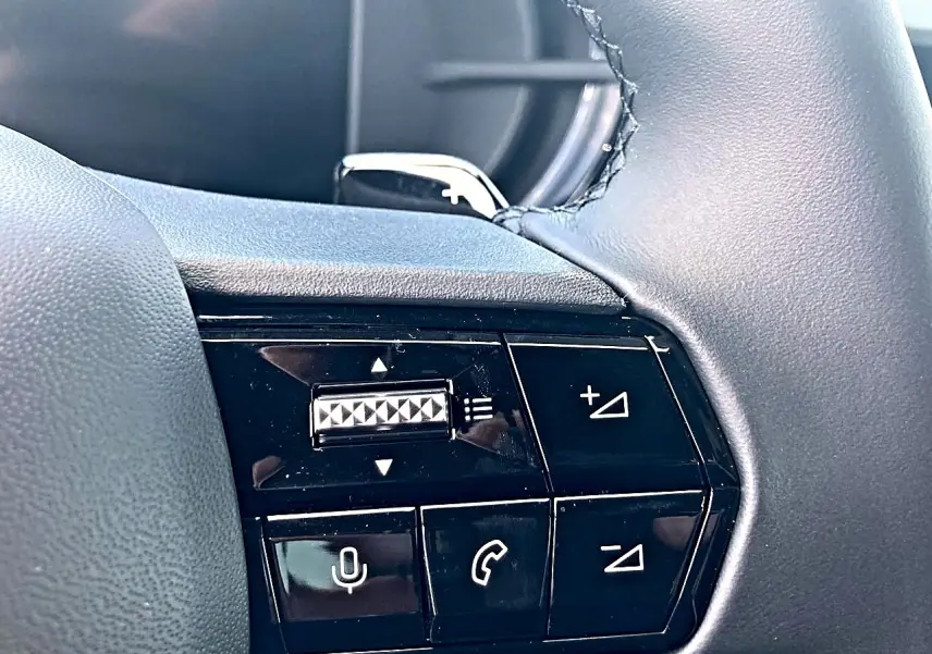 Gros plan sur les commandes du volant côté droit de l'Alfa Romeo Junior gris, avec boutons de volume et appels.