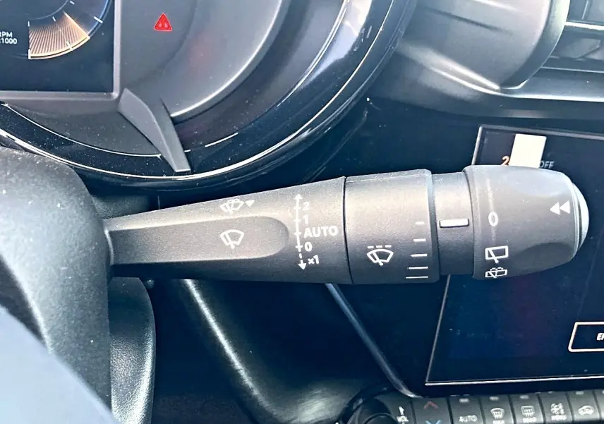 Gros plan sur la commande des essuie-glaces à gauche du volant dans l’habitacle gris de l’Alfa Romeo Junior 1.2 hybride 2026.