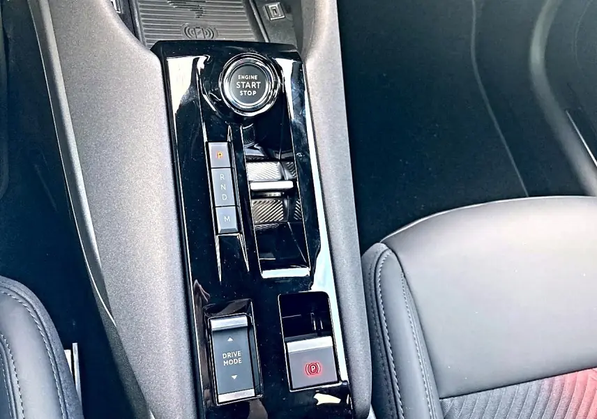 Vue rapprochée de la console centrale noire brillante avec bouton start/stop et levier de boîte automatique sur Alfa Romeo Junior gris.