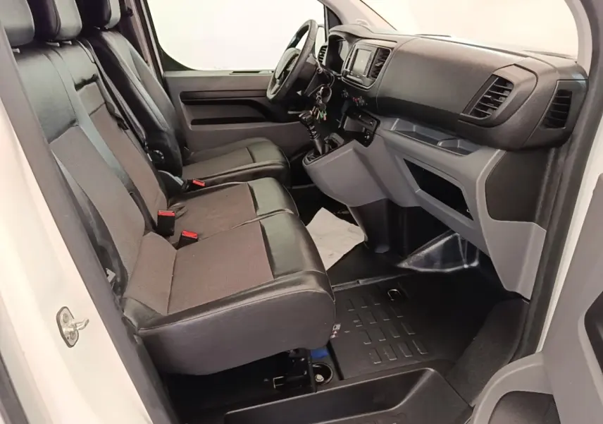 Vue intérieure côté conducteur du Peugeot Expert Fourgon blanc, montrant les sièges avant et le tableau de bord.