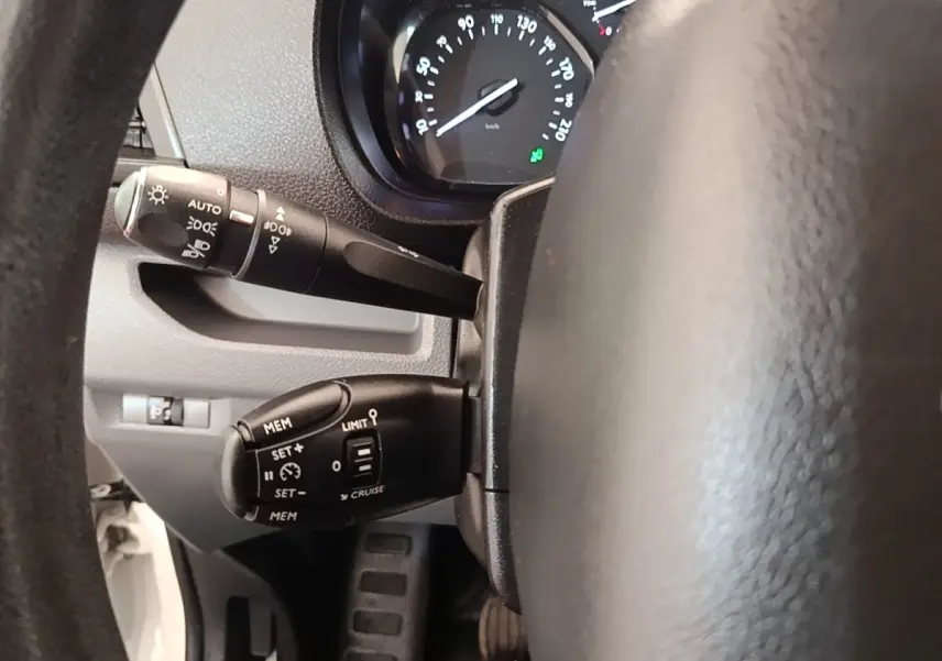 Vue rapprochée du volant côté gauche du Peugeot Expert Fourgon blanc, montrant commandes de régulateur et éclairage.
