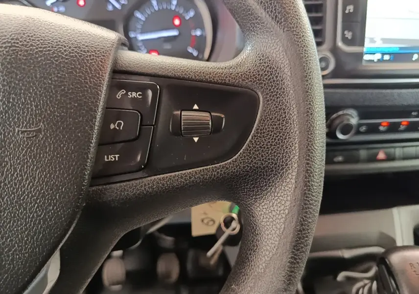Gros plan sur le volant noir du Peugeot Expert Fourgon 2020, avec commandes audio et tableau de bord en arrière-plan.