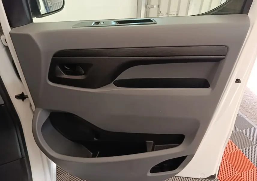 Vue rapprochée de la porte intérieure côté conducteur du Peugeot Expert Fourgon blanc, avec poignée noire et rangements intégrés.