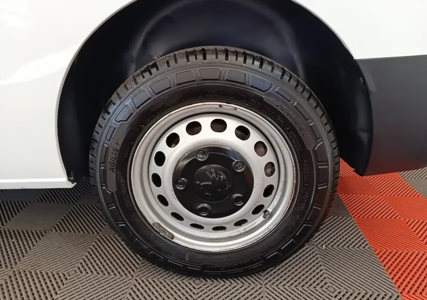 Gros plan sur la roue arrière droite en jante acier du Peugeot Expert Fourgon blanc, avec logo Peugeot visible au centre.