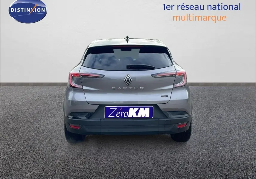 Vue arrière d'un Renault Captur E-Tech hybride gris cassiopée avec toit noir, immatriculé Zero KM, sur fond neutre.