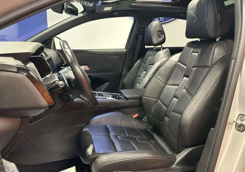 Vue intérieure côté conducteur du DS7 2024 avec sièges cuir noirs et toit ouvrant visible au-dessus.