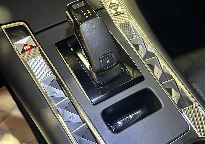 Gros plan sur la console centrale du DS7 2024 avec levier de boîte auto et commandes en finition noire brillante.