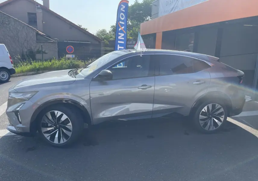 Vue latérale gauche d'une Renault Rafale 2025 gris métallisé avec toit noir, jantes modernes et lignes dynamiques.