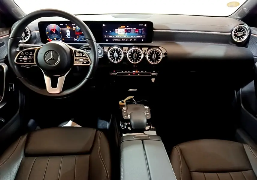 Vue intérieure avant de la Mercedes Classe A A 200 d Progressive Line 2022, tableau de bord noir avec écran tactile et volant cuir.