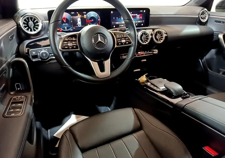 Vue intérieure avant de la Mercedes Classe A 200 d Progressive Line 2022, tableau de bord numérique et volant cuir noir.