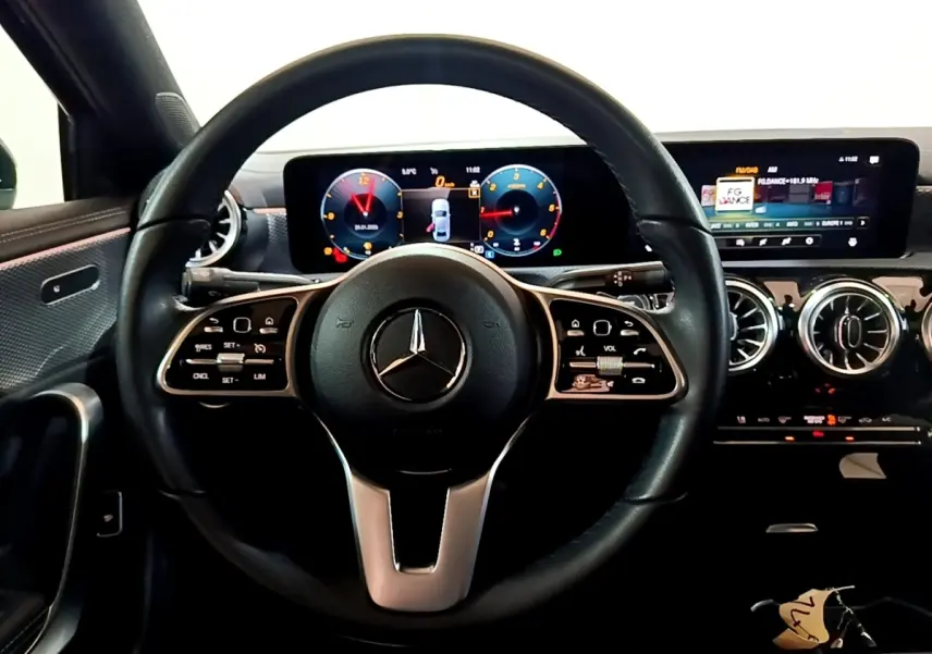 Vue intérieure centrée sur le volant cuir noir et le tableau de bord numérique de la Mercedes Classe A berline 2022.