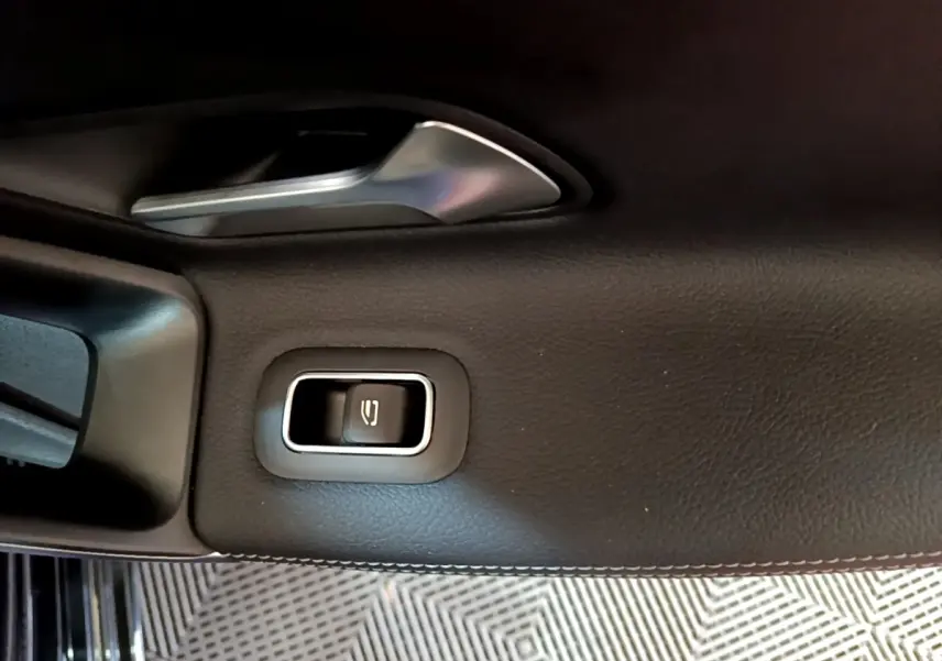 Détail de la commande électrique de la lunette arrière sur la porte intérieure côté gauche d’une Mercedes Classe A noire.