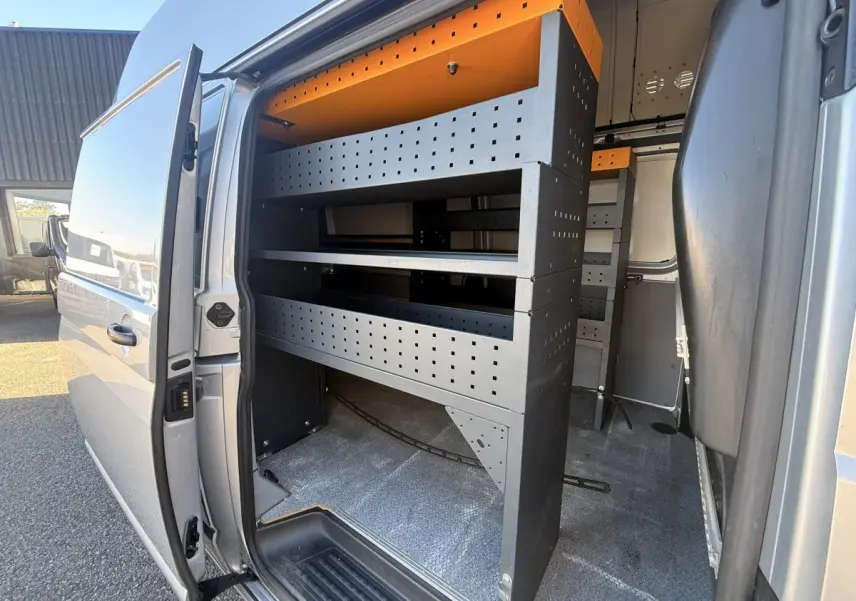 Vue latérale droite du Volkswagen Transporter gris clair 2022 avec porte coulissante ouverte et aménagements de rangement internes.