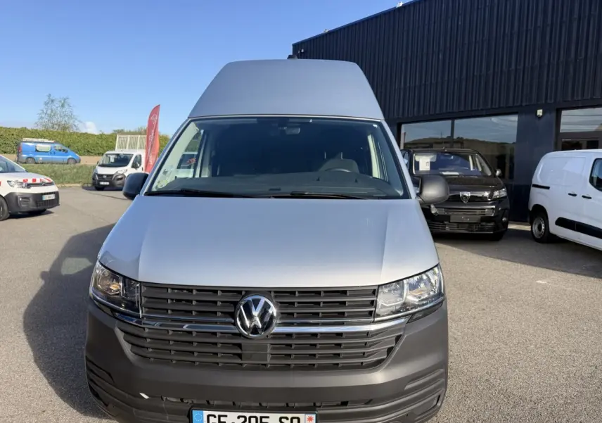 Vue avant d'un Volkswagen Transporter gris clair 2.0 TDi 110 L2H1 Business avec calandre noire et logo VW central.