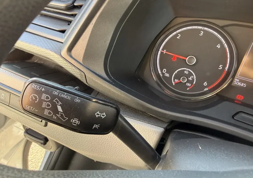 Gros plan sur le levier de commande du régulateur de vitesse et le compte-tours du tableau de bord du Volkswagen Transporter gris clair.