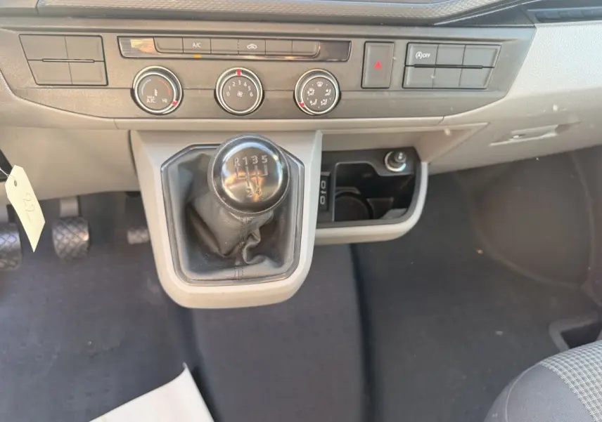 Gros plan sur la console centrale grise du Volkswagen Transporter 2.0 TDi 110 avec levier de vitesse manuel et commandes climatisation.