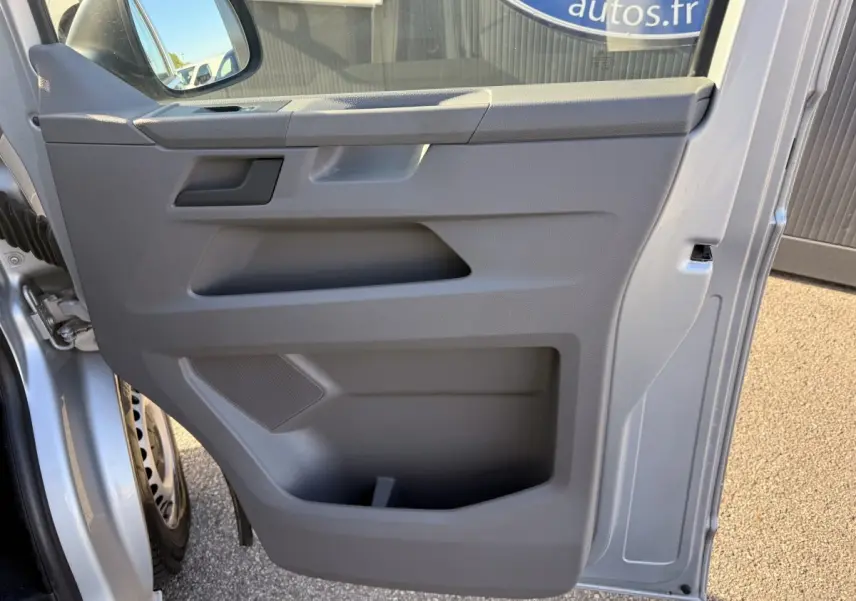 Vue rapprochée de la porte avant gauche grise claire du Volkswagen Transporter 2.0 TDi 110 L2H1 Business avec rangement intégré.