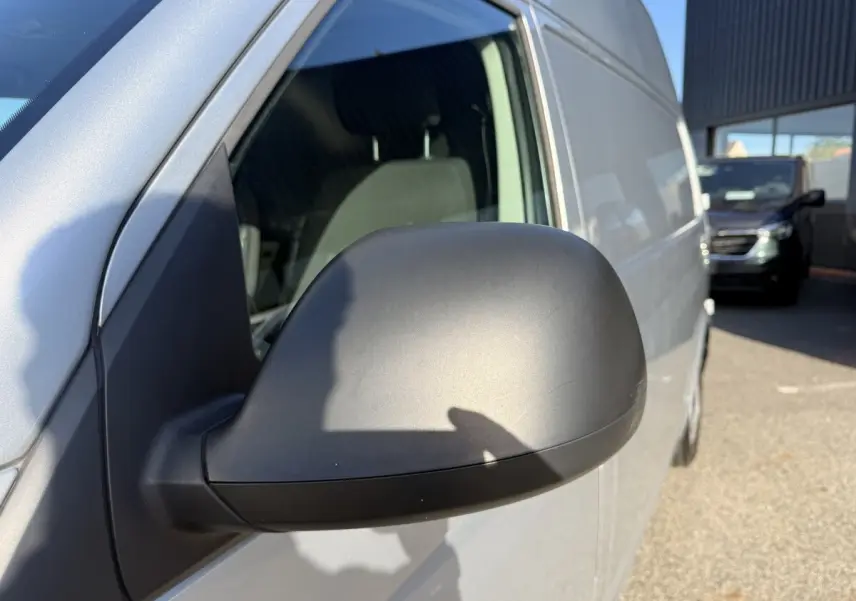 Gros plan sur le rétroviseur côté gauche du Volkswagen Transporter gris clair, vue latérale avant droite.