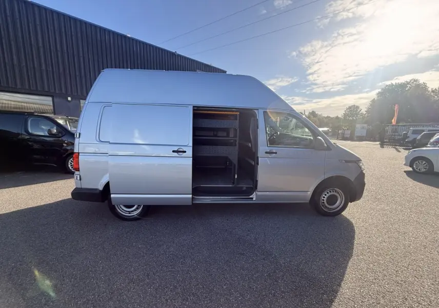 Vue latérale droite d’un Volkswagen Transporter gris clair 2022 avec porte coulissante ouverte montrant l’intérieur aménagé.