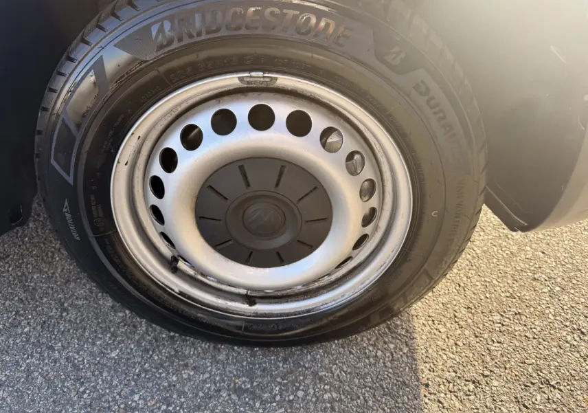Gros plan sur la roue avant droite du Volkswagen Transporter gris clair avec jante acier et pneu Bridgestone.