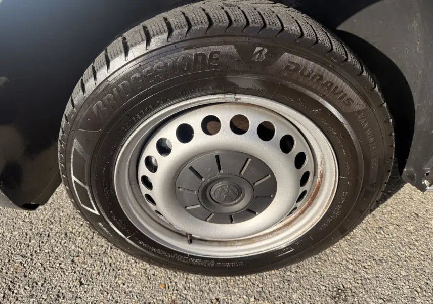 Gros plan sur la roue acier grise avec pneu Bridgestone hiver du Volkswagen Transporter gris clair 2022.