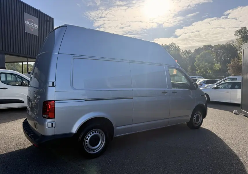 Vue 3/4 arrière droit d’un Volkswagen Transporter gris clair L2H1 avec grande hauteur de toit, stationné en extérieur.
