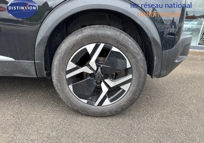 Gros plan sur la roue avant droite noire métal d'un Peugeot 2008 Hybrid 136ch Allure avec jante bi-ton distinctive.