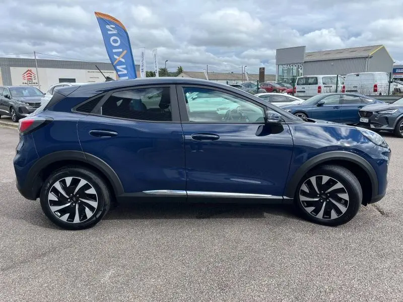 Profil côté gauche d'un Ford Puma bleu Abysse 2023 avec jantes alliage bicolores et vitres arrière surteintées.