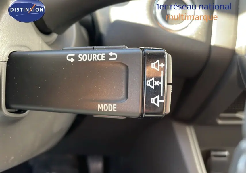 Gros plan sur la commande au volant du Renault Captur E-Tech hybride 2025, avec boutons source et mode visibles.