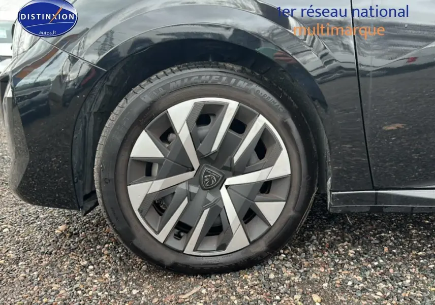 Vue latérale côté gauche d'une Peugeot 208 noire 2025, mettant en valeur la roue avant et la carrosserie brillante.