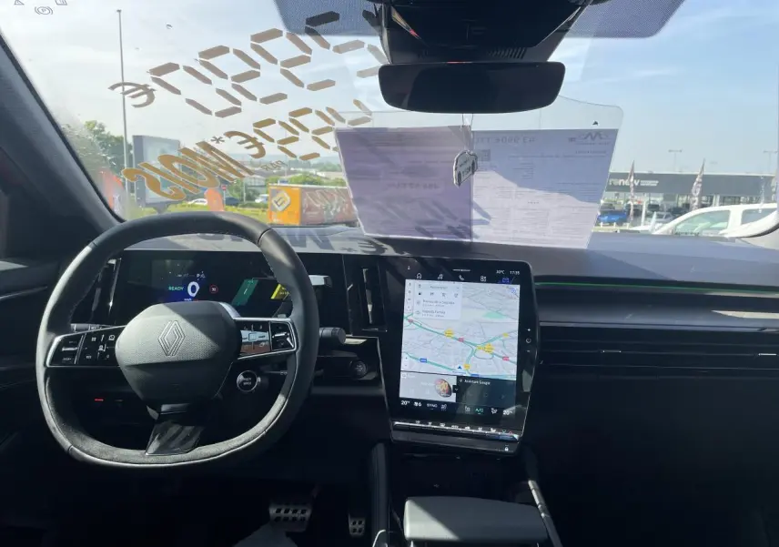 Vue intérieure avant du Renault Rafale 2025, volant Alcantara avec logo, écran tactile vertical affichant la navigation.