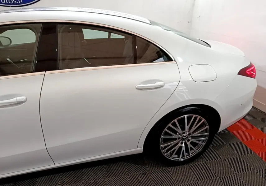 Vue côté droit arrière d'une Mercedes CLA 200 d Business Line blanche avec jante alliage et feux LED allumés.