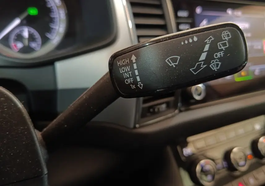 Gros plan sur la commande des essuie-glaces dans l’habitacle du Skoda Kodiaq blanc, tableau de bord en arrière-plan flou.